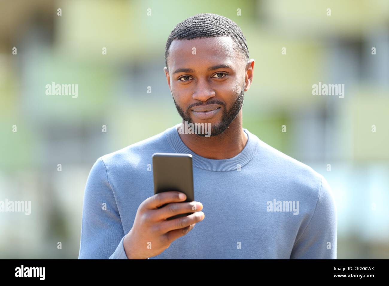 Un homme à la peau noire vous regarde en tenant le téléphone Banque D'Images
