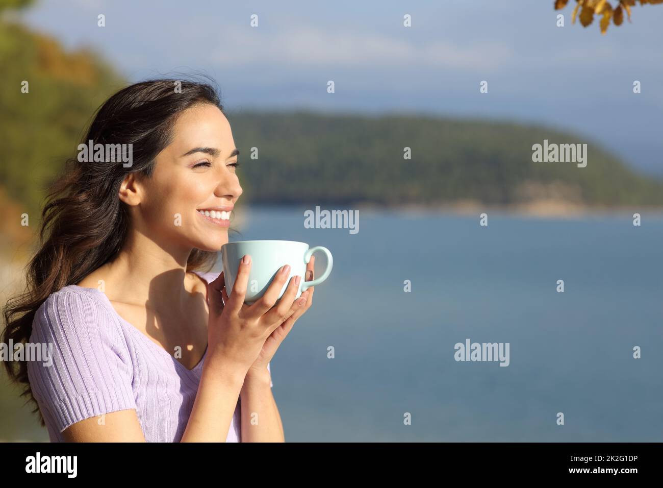 Bonne femme buvant un café en regardant loin dans la nature Banque D'Images