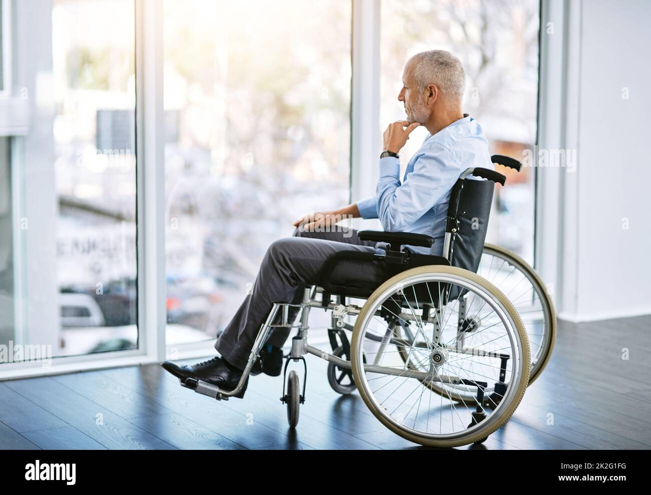 Je manque l'époque de la mobilité. Photo d'un homme mûr assis dans un fauteuil roulant et regardant par la fenêtre. Banque D'Images
