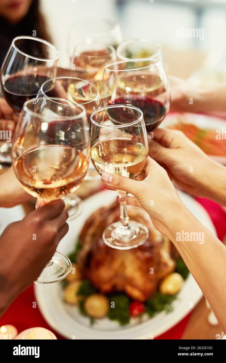 Le vin se Marie bien avec de bons amis. Photo d'un groupe de personnes faisant un toast à une table de salle à manger. Banque D'Images