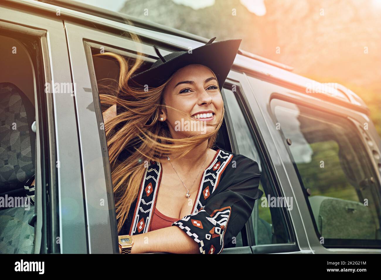 Profitez simplement du voyage de la vie. Prise de vue courte d'une jeune femme qui s'est penchée hors de la fenêtre d'une voiture lors d'un voyage en voiture. Banque D'Images