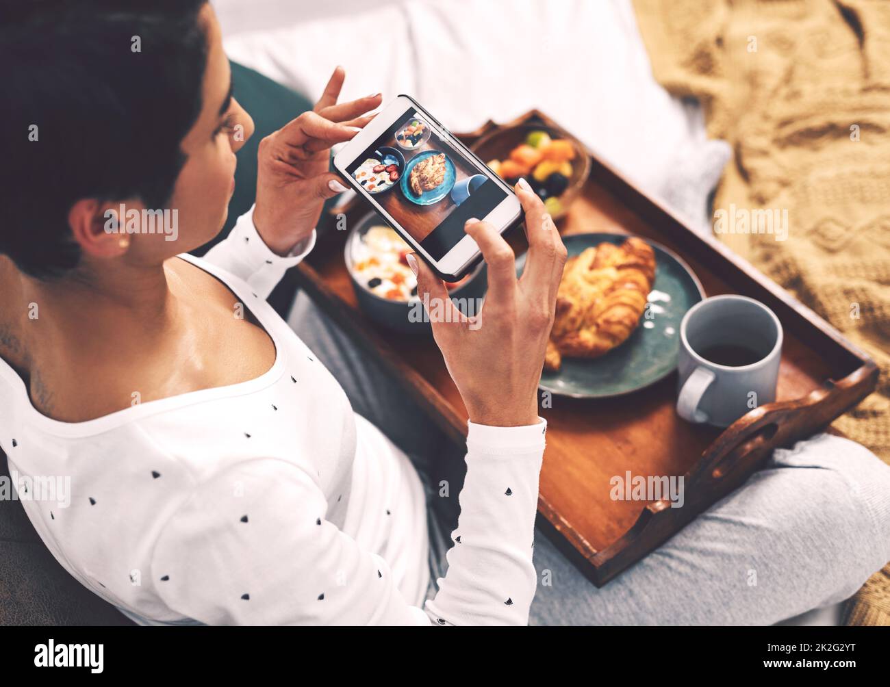 Faites-le pour le gramme. Prise de vue rognée d'une jeune femme attirante utilisant son téléphone portable pour prendre une photo de son plateau de petit déjeuner à la maison. Banque D'Images