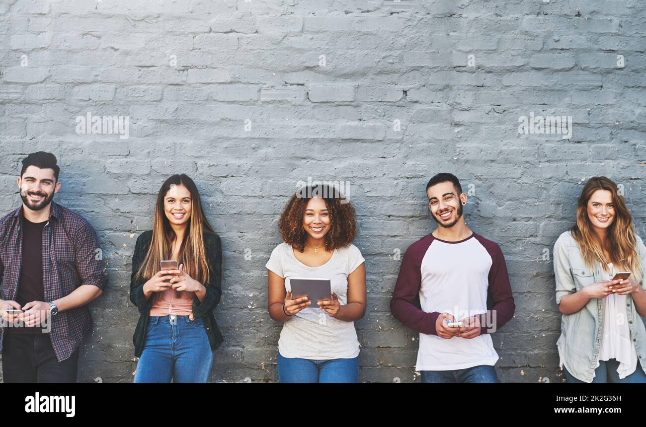 Accès à l'information, où et quand nous le voulons. Portrait d'un groupe de jeunes utilisant leurs appareils sans fil ensemble à l'extérieur. Banque D'Images