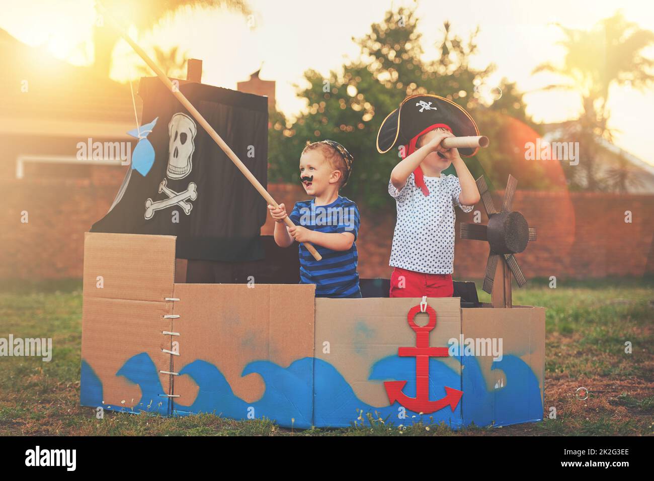 Ces petits pirates veulent juste à Amuse-toi bien. Photo d'un petit garçon mignon et de son frère jouant des pirates dehors sur un bateau fait de boîtes en carton. Banque D'Images