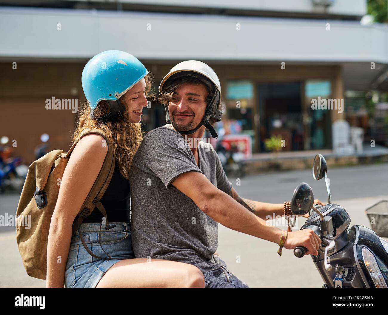 Partez à l'aventure. Photo de deux heureux routards à cheval sur une moto à travers une ville étrangère. Banque D'Images