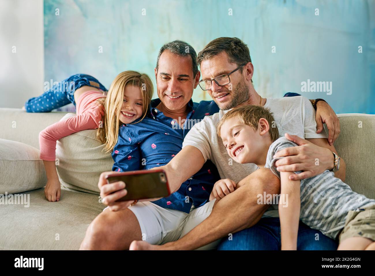 Entrer ici, ont pris un selfie. Photo courte d'une famille affectueuse de quatre personnes prenant des selfies sur le canapé à la maison. Banque D'Images