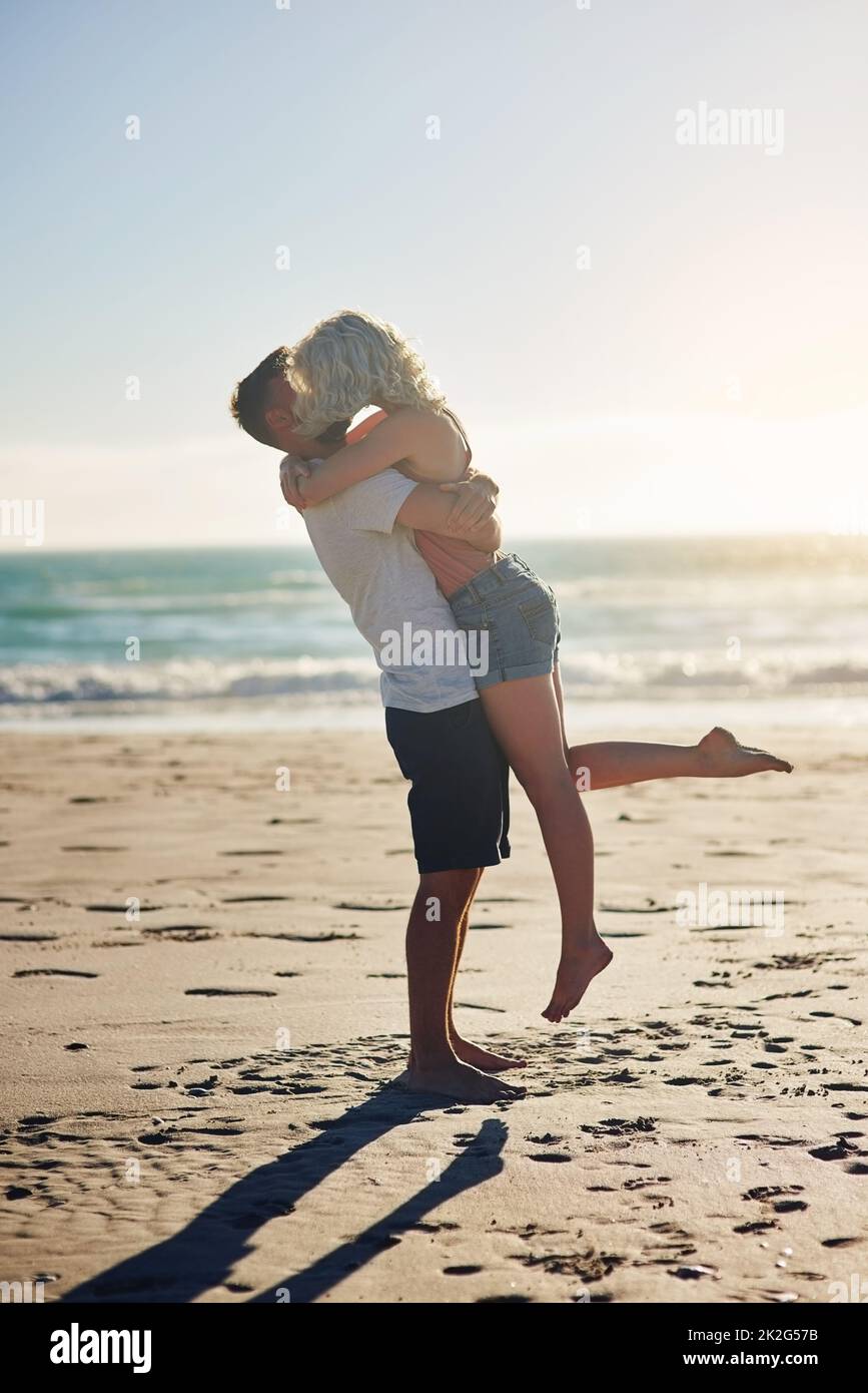 Nous avons ce genre d'amour spécial. Photo d'un couple aimant partageant un baiser tout en passant du temps à la plage. Banque D'Images