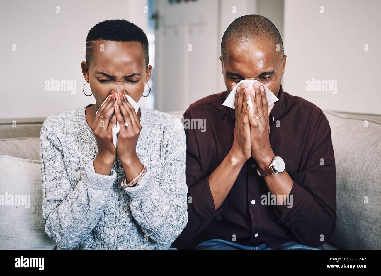 Étaient aussi malades que les chiots aujourd'hui. Prise de vue d'un jeune couple malade soufflant le nez avec des tissus à la maison. Banque D'Images