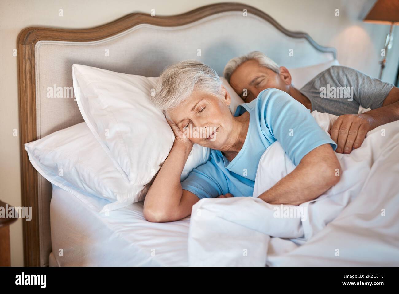 Les vieilles habitudes ne meurent jamais. Photo courte d'un couple affectueux et âgé se câliner tout en dormant au lit dans une maison de soins infirmiers. Banque D'Images