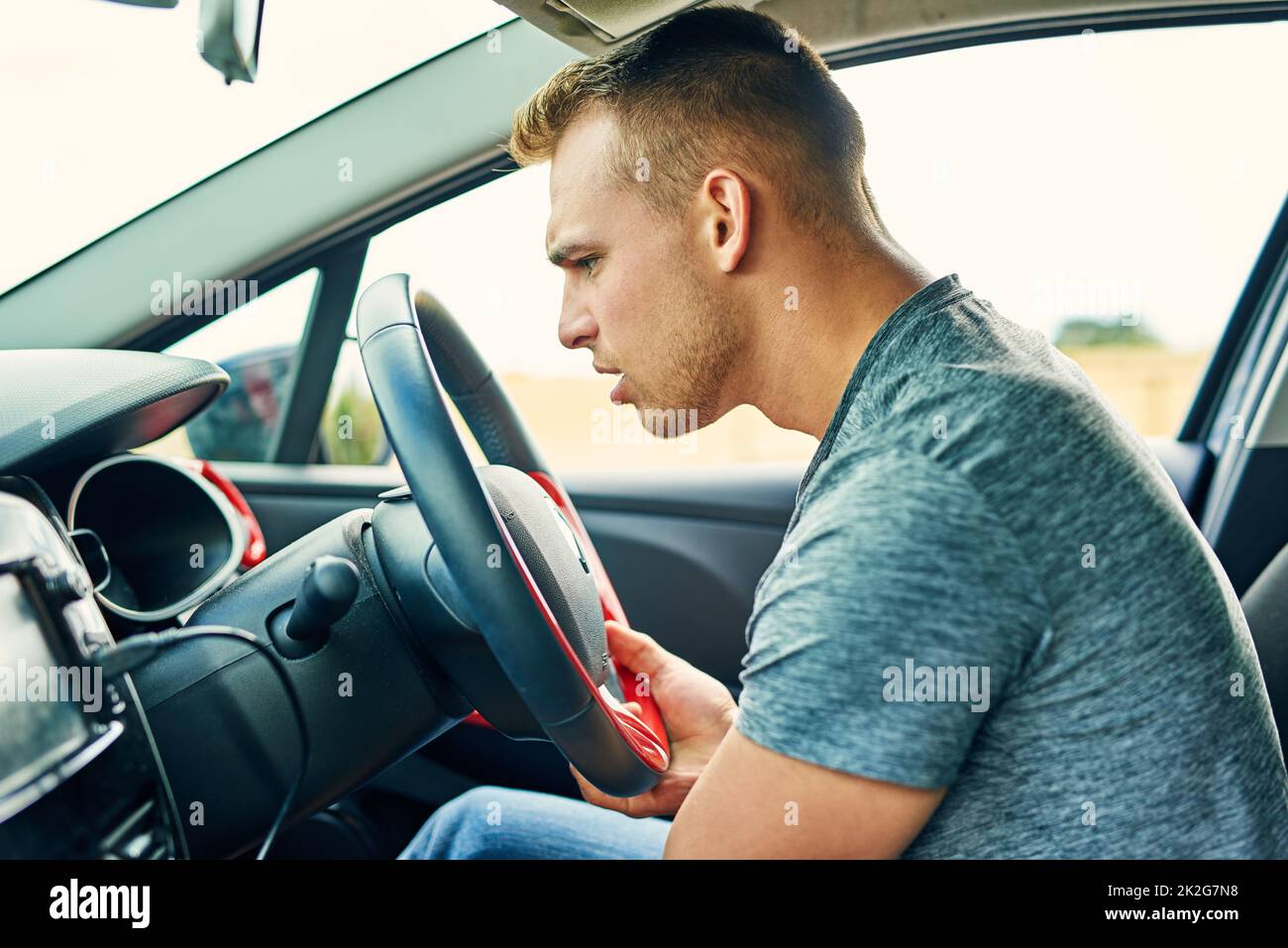 Ce qui fait ce son drôle. Photo d'un jeune homme ayant des problèmes avec sa voiture en conduisant. Banque D'Images