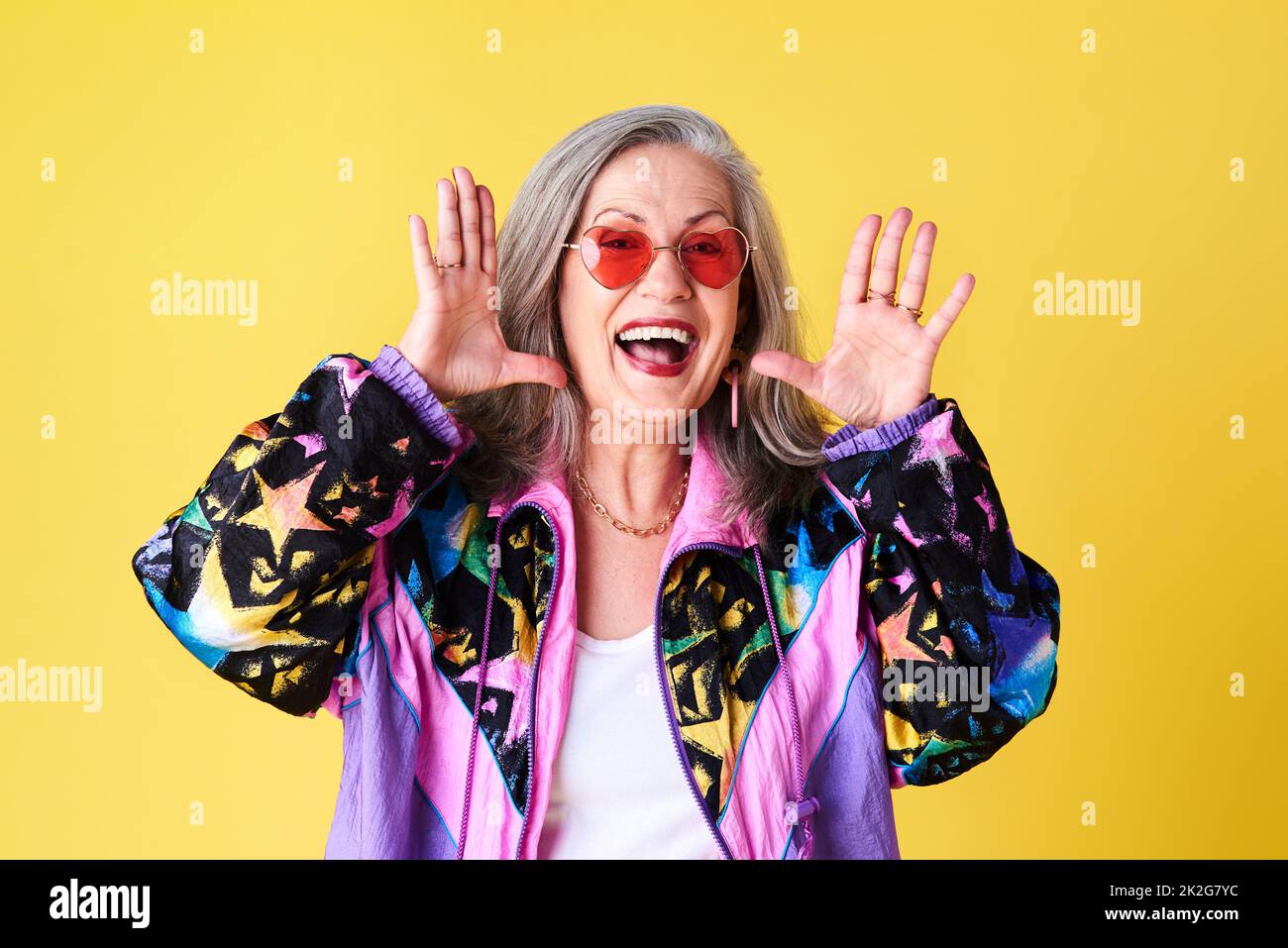 Bonjour jeune monde. Photo courte d'une femme âgée confiante et élégante portant des lunettes de soleil se posant sur un fond jaune. Banque D'Images