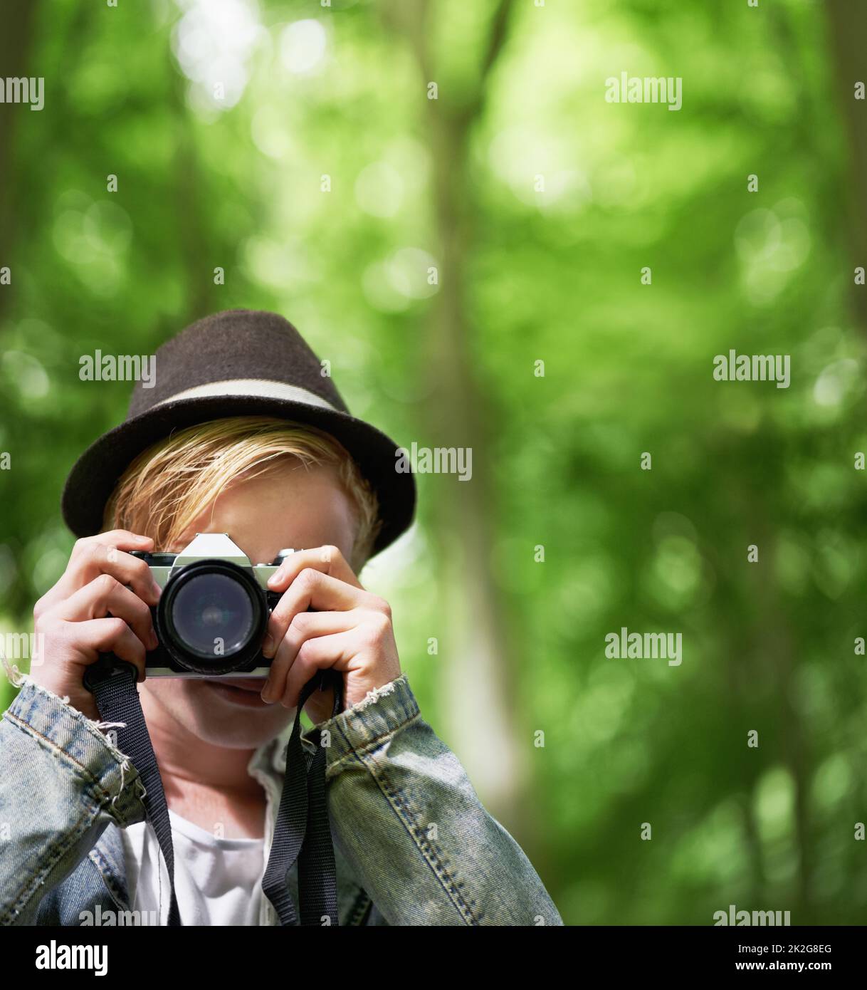 Capturez la photo parfaite. Gros plan portrait d'un jeune homme prenant des photos avec un appareil photo d'époque dans la forêt. Banque D'Images