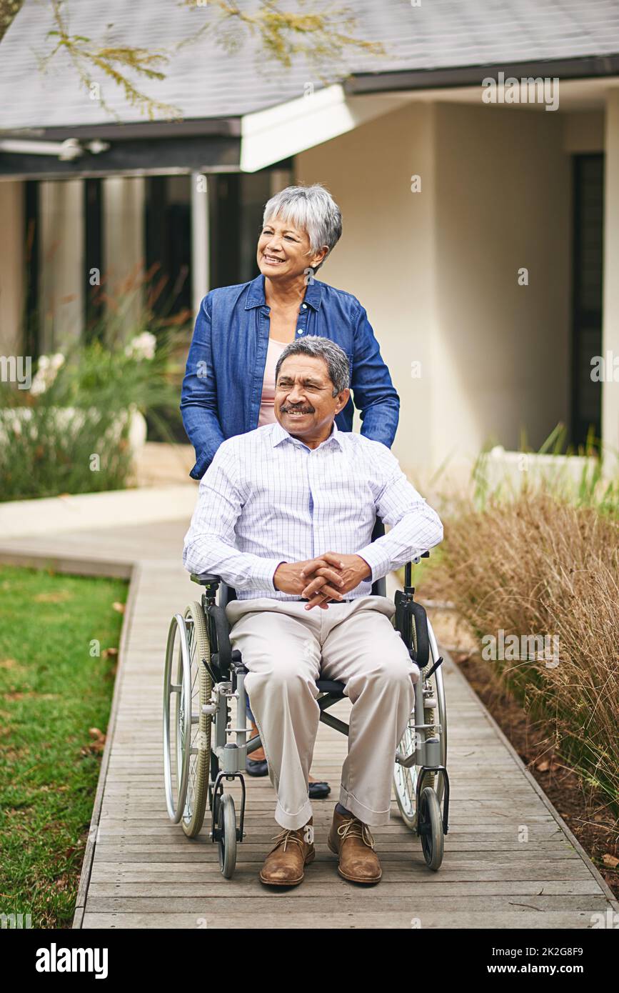 Pour une promenade. Photo d'une femme âgée poussant son mari dans un fauteuil roulant à l'extérieur. Banque D'Images