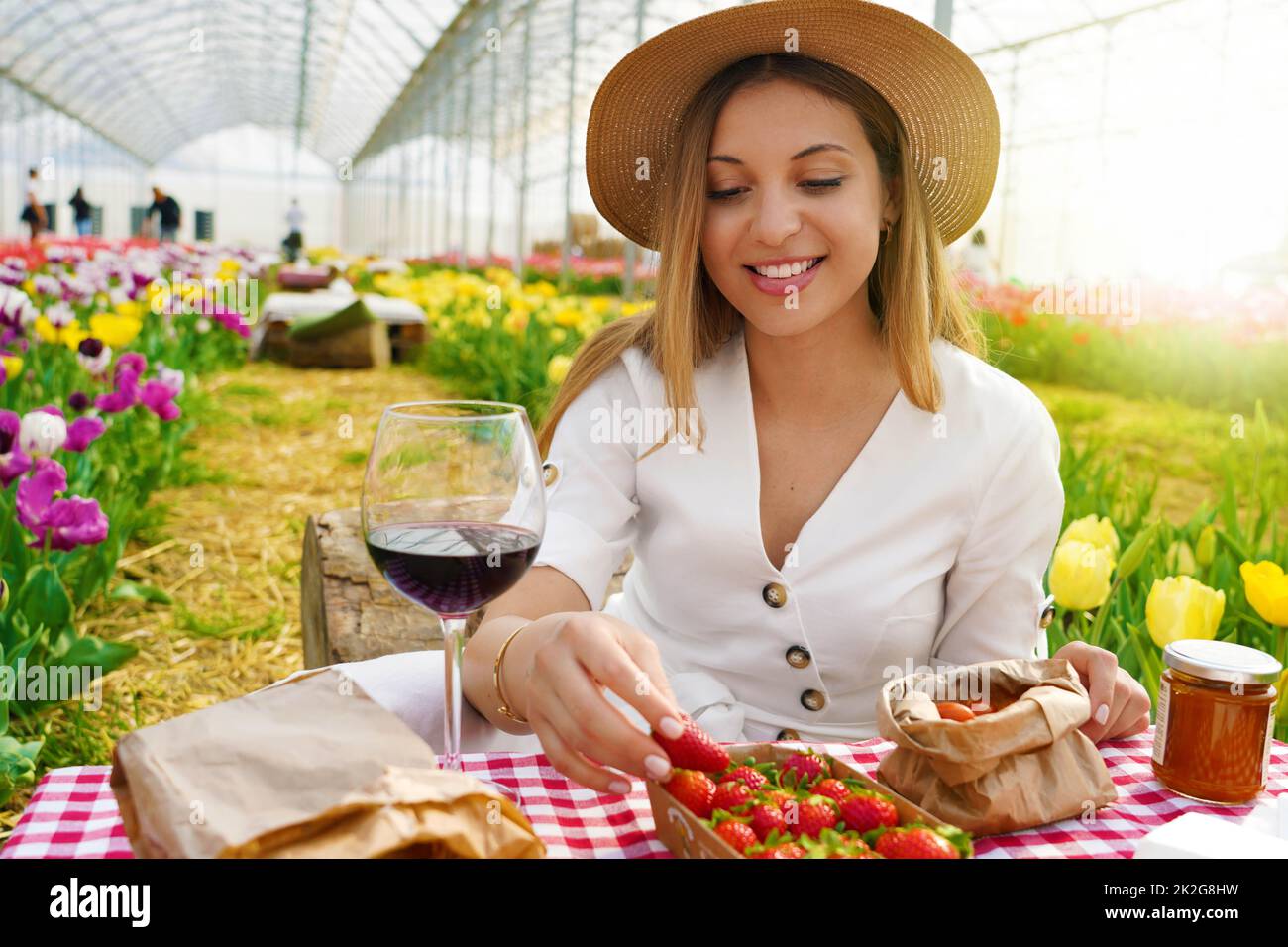 Pique-nique entre tulipes au printemps. Belle femme assise entre des fleurs appréciant des aliments locaux biologiques en Toscane, Italie. Banque D'Images