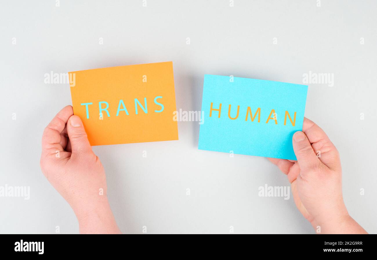 Le mot transhuman est debout sur deux morceaux de papier, tenant le message entre les mains, la technologie future, post-humain, la science, la transformation Banque D'Images