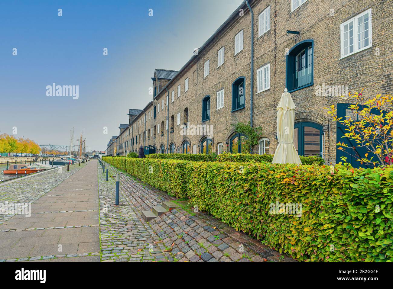 De nombreux bâtiments de trois étages en briques grises sur une rue avec un pavé en pierre près du canal de la rivière, dans le quartier Christianshavn.Copenhagen, Danemark Banque D'Images