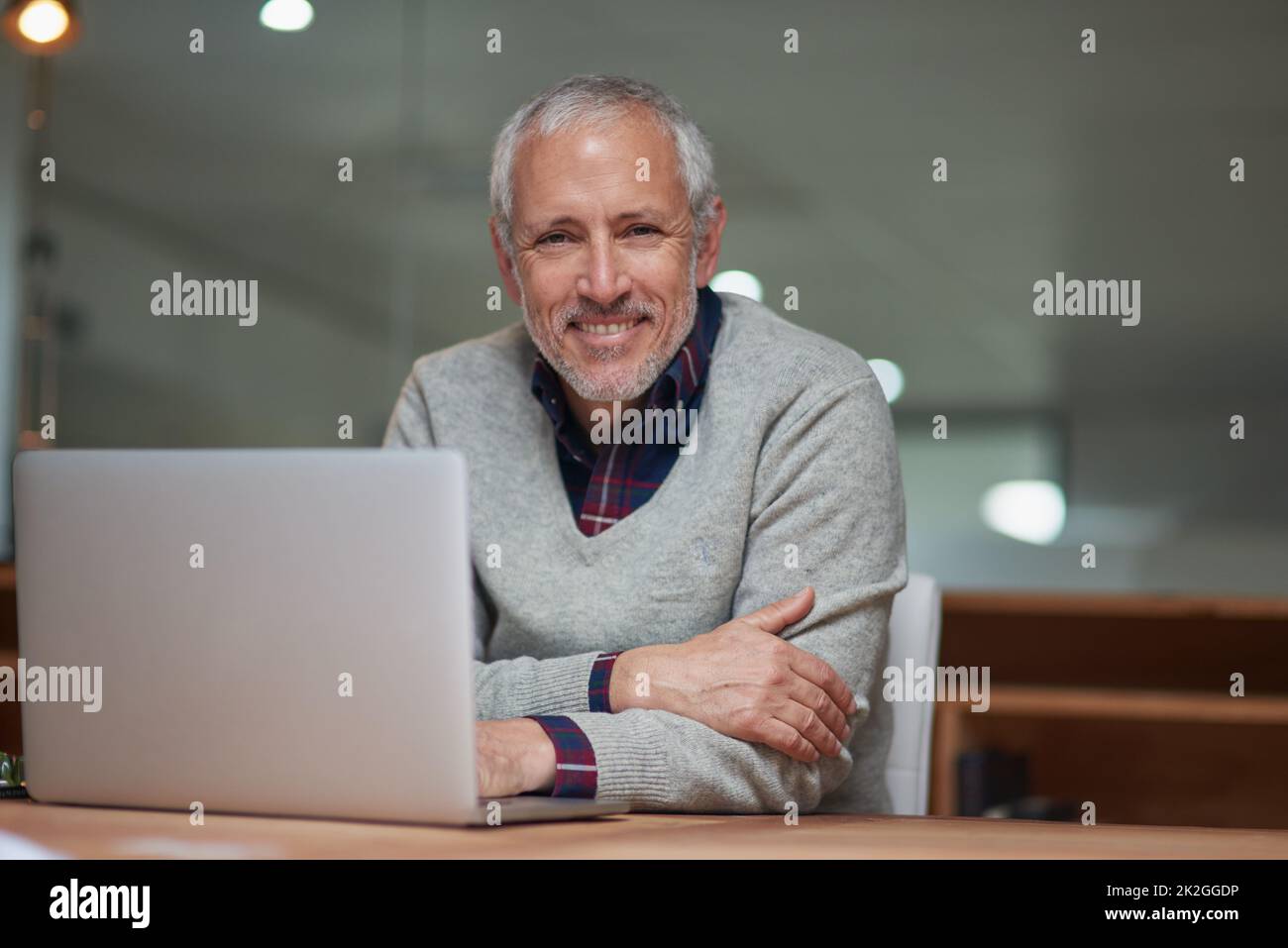 Les hauts et les bas des affaires. Portrait d'un homme d'affaires mûr souriant utilisant un ordinateur portable tout en travaillant dans un bureau. Banque D'Images
