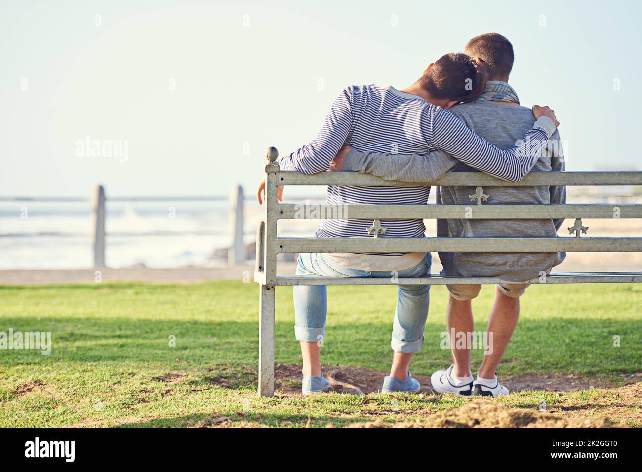 Prendre un après-midi romantique. Vue arrière d'un jeune couple gay assis ensemble sur un banc de parc. Banque D'Images
