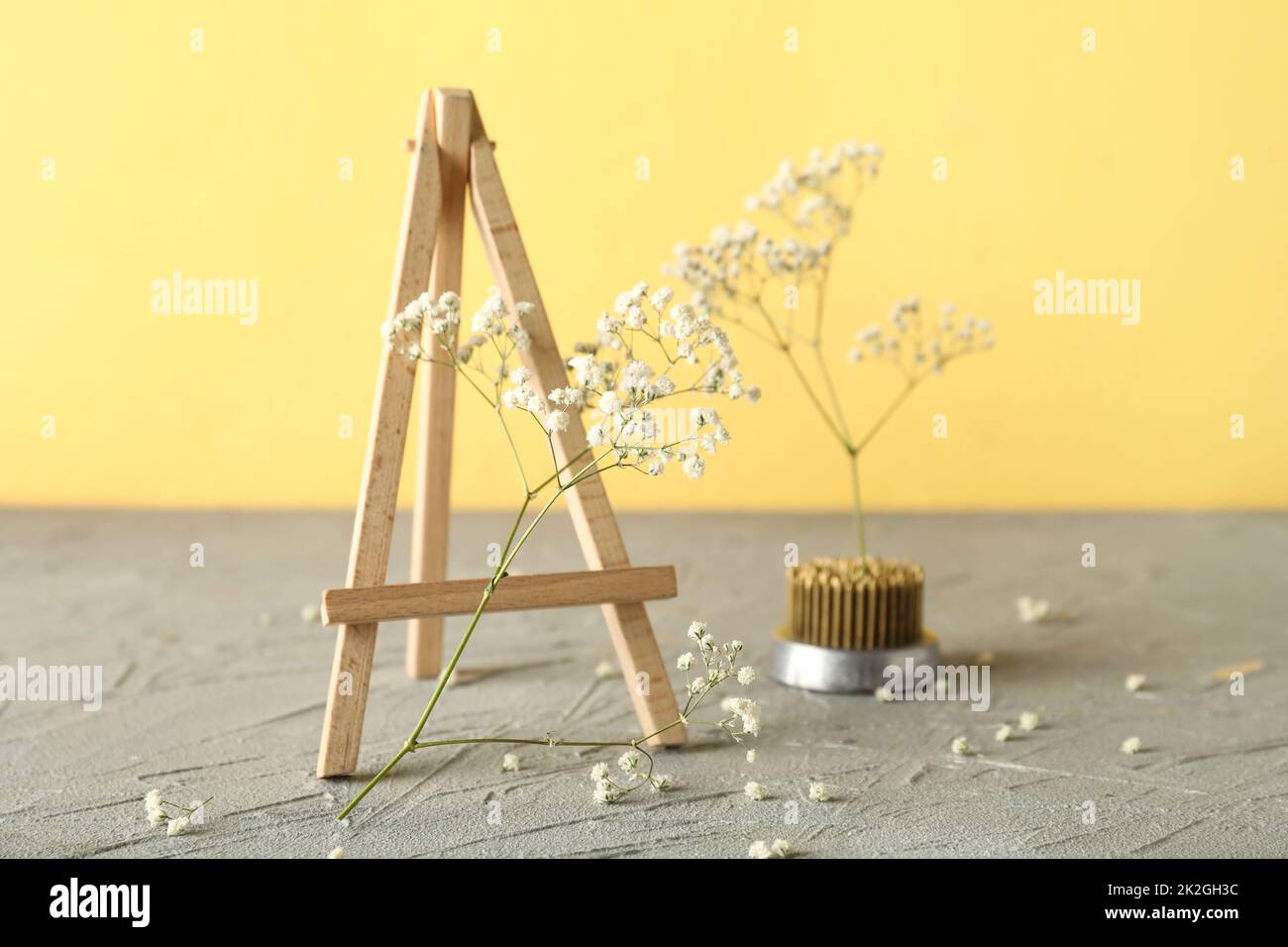 Chevalet avec fleurs et kenzan pour ikebana sur la table près du mur jaune Banque D'Images