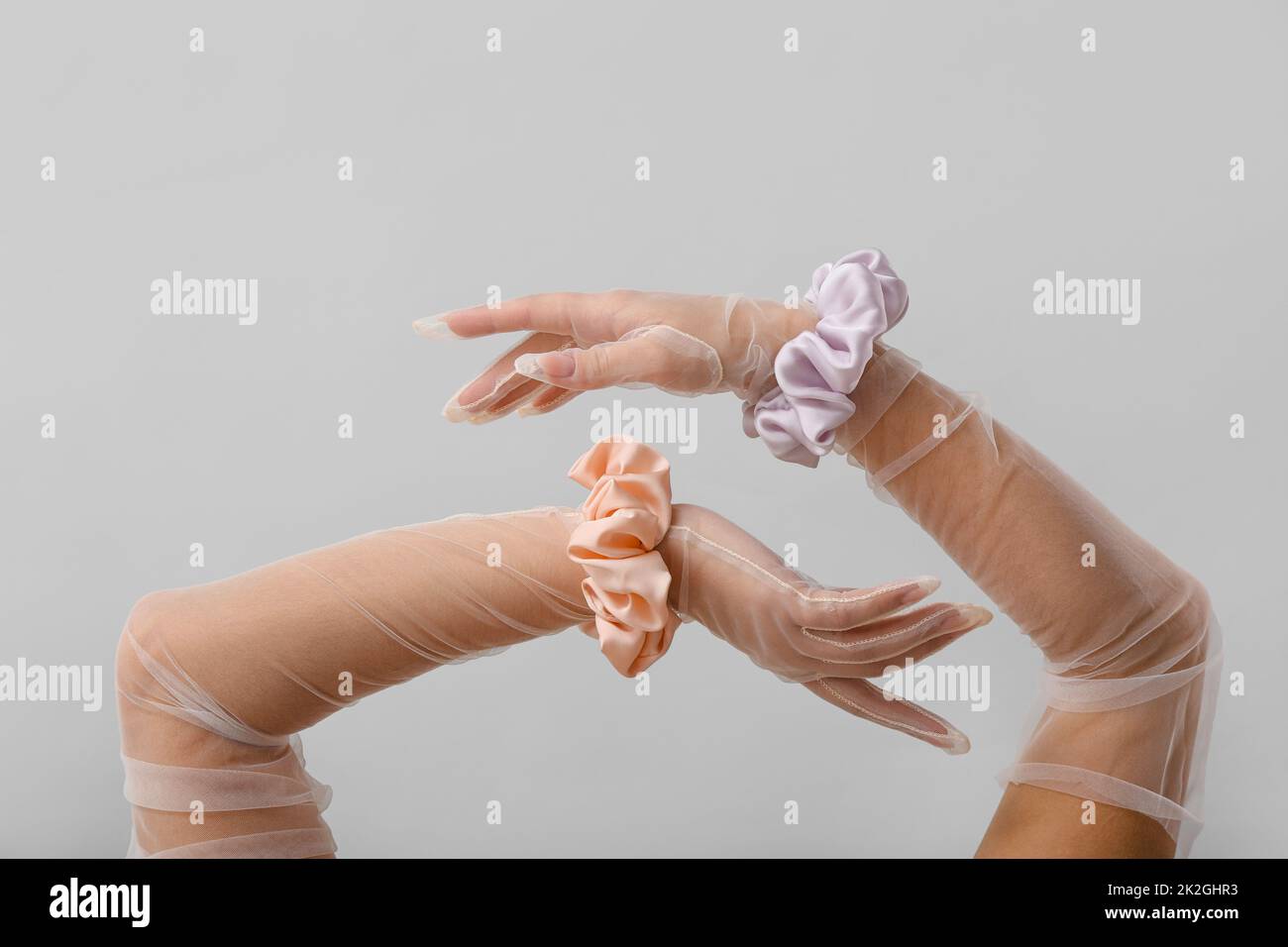 Female hands in gloves with silk scrunchies on light background Banque D'Images