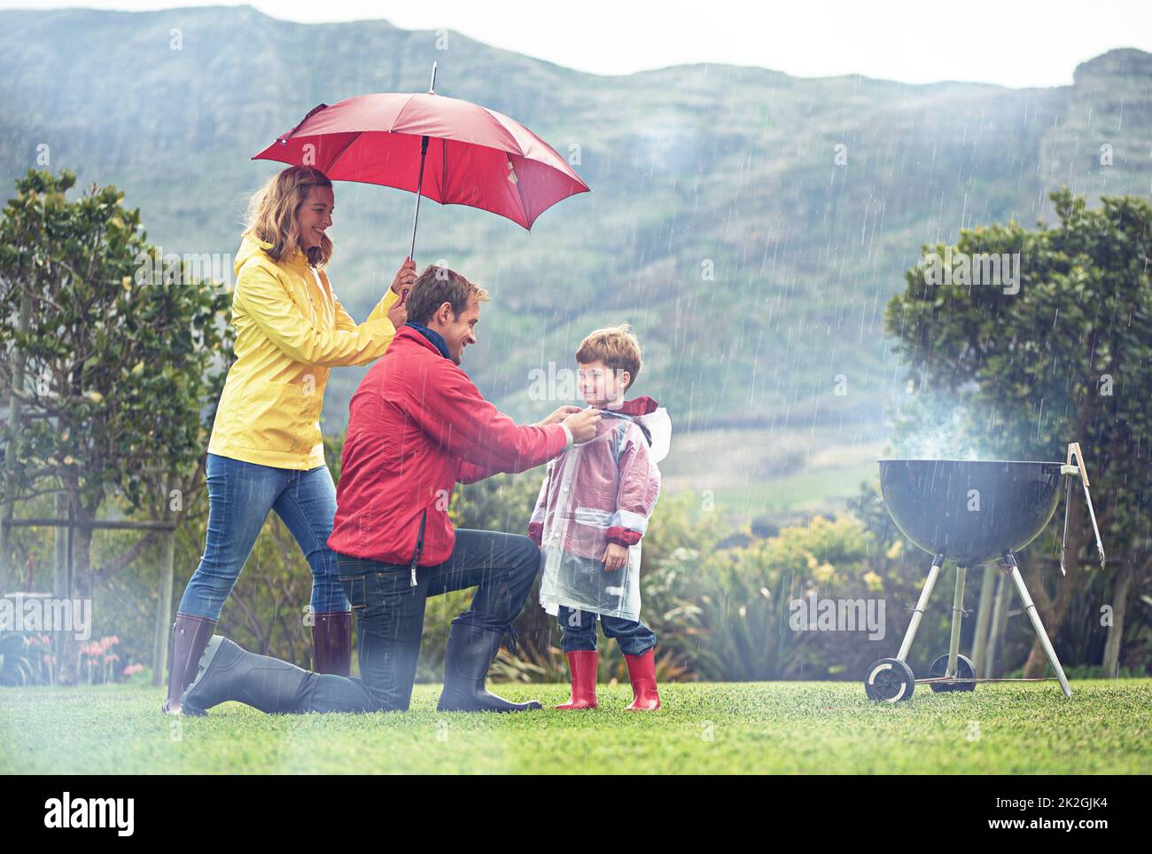 La pluie ne les empêche pas de s'amuser. Photo d'une famille ayant un barbecue à l'extérieur par temps pluvieux. Banque D'Images