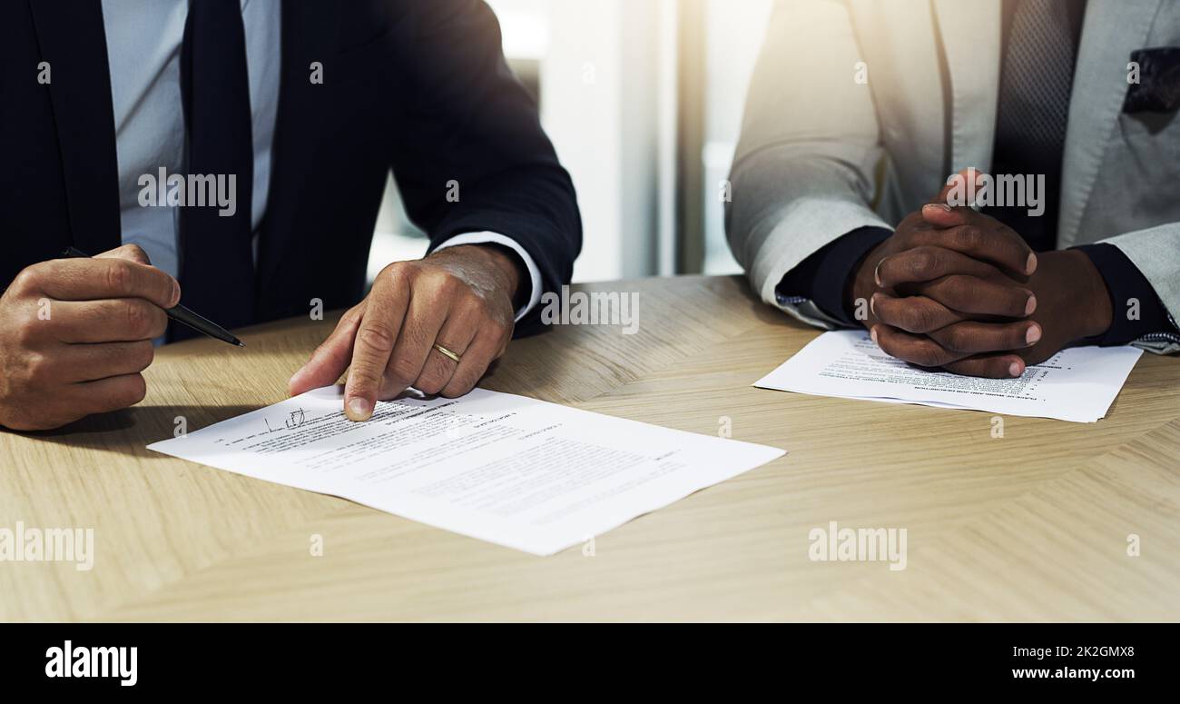 Examen de leur accord. Gros plan de deux hommes d'affaires non identifiables passant par la paperasse dans un bureau. Banque D'Images