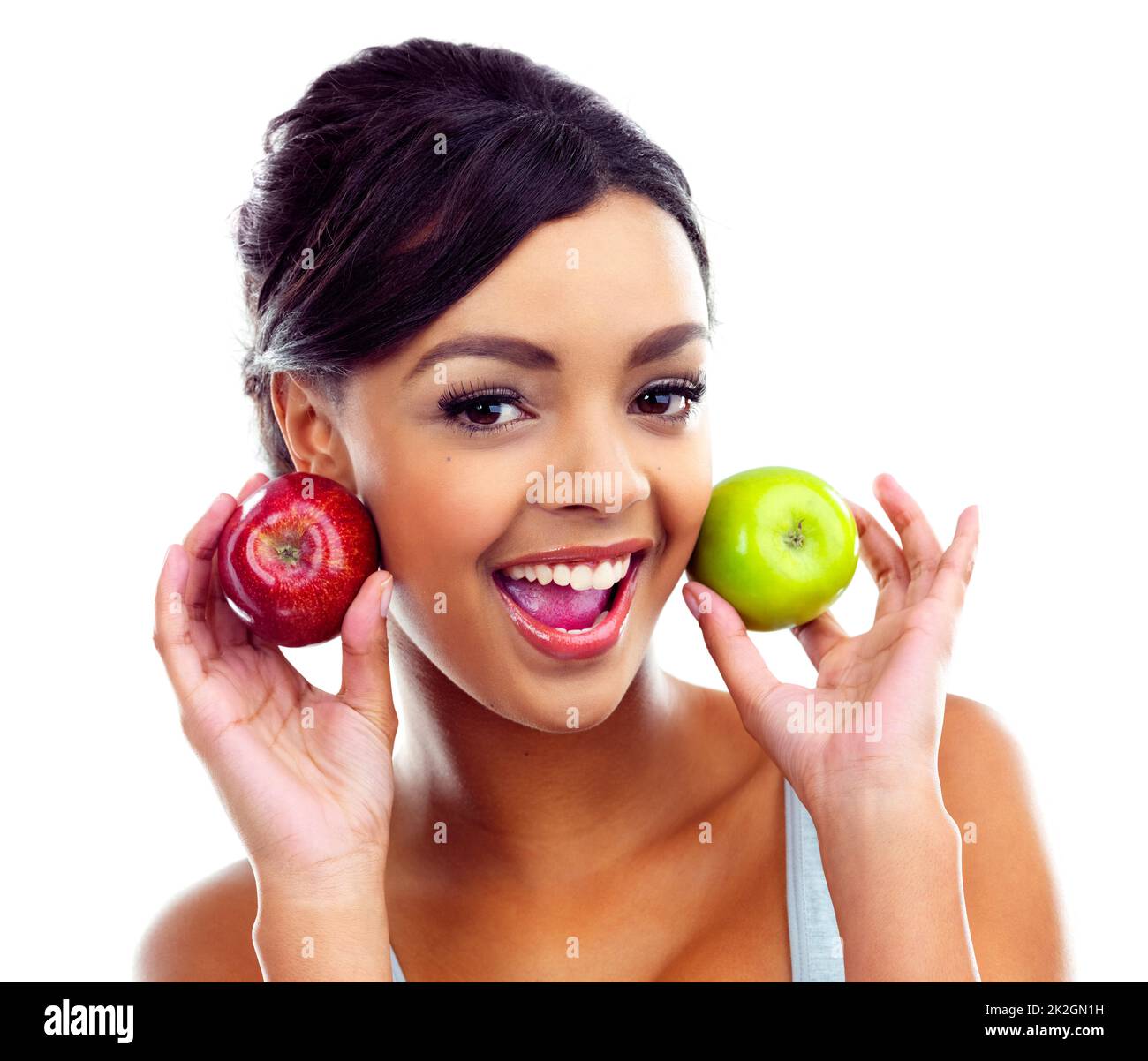 Shes dans une saine alimentation. Une jeune femme en tenue de gymnastique tenant deux pommes et souriant à la caméra. Banque D'Images