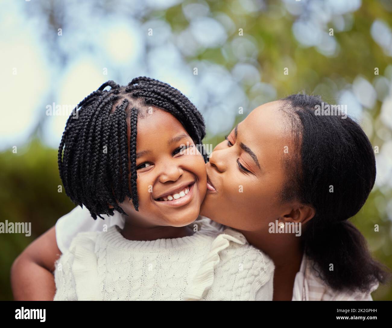 Avoir une mère signifie avoir un meilleur ami pour la vie. Photo d'une jeune mère donnant un baiser à sa fille dans la nature. Banque D'Images