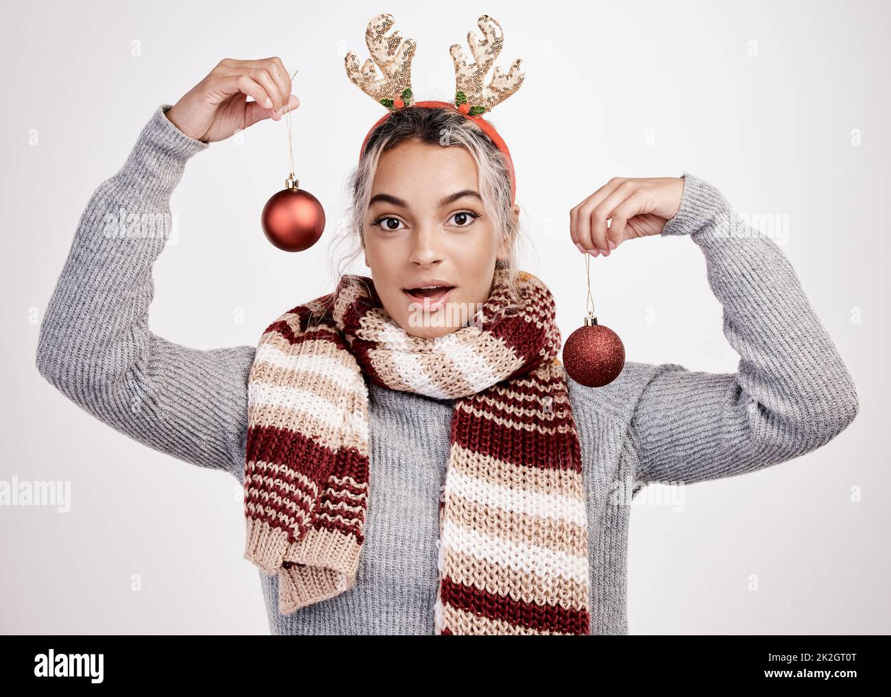 Laisse la décoration. Portrait studio d'une jeune femme attrayante tenant des boules tout en portant une tenue de Noël. Banque D'Images