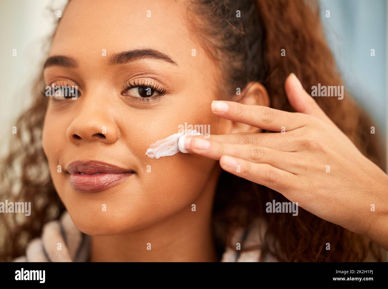 C'est ainsi que je le garde doux et lumineux. Plan court d'une belle jeune femme appliquant un hydratant sur son visage. Banque D'Images