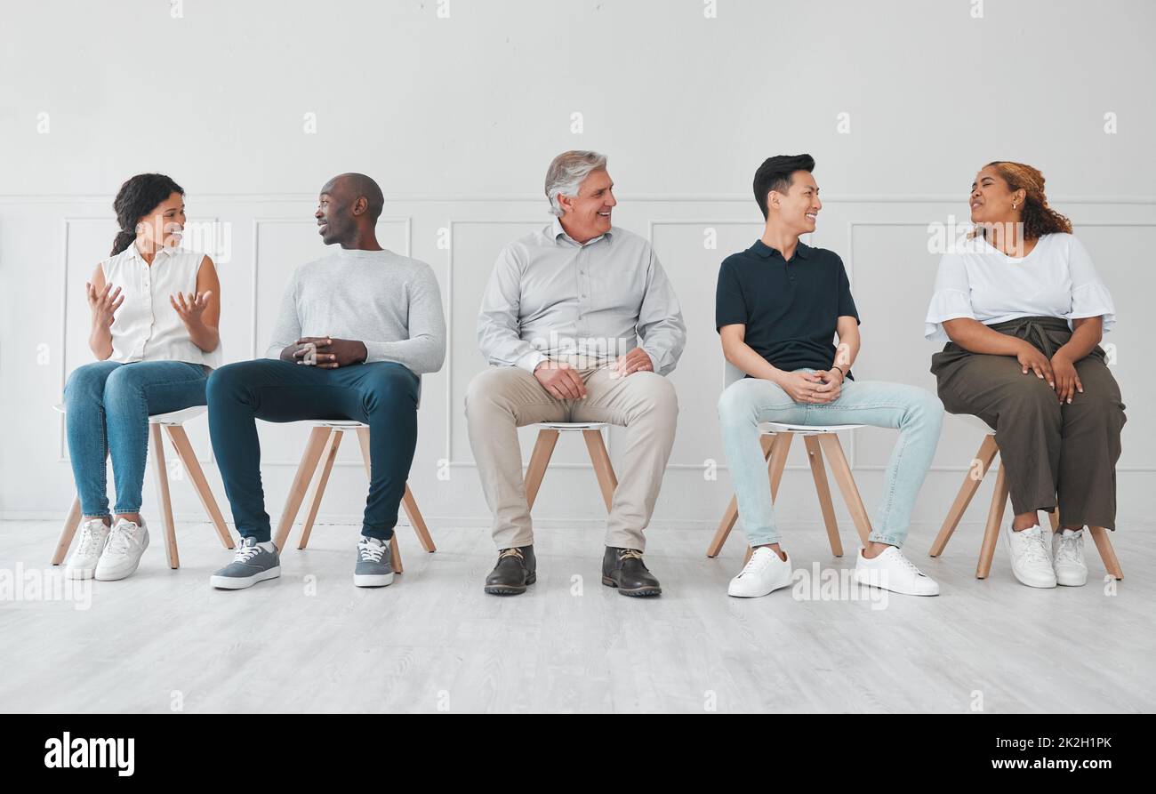 Nous pouvons apprendre beaucoup en écoutant les histoires des autres. Photo d'un groupe diversifié de personnes qui parlent les unes aux autres tout en étant assis dans la ligne sur un fond blanc. Banque D'Images