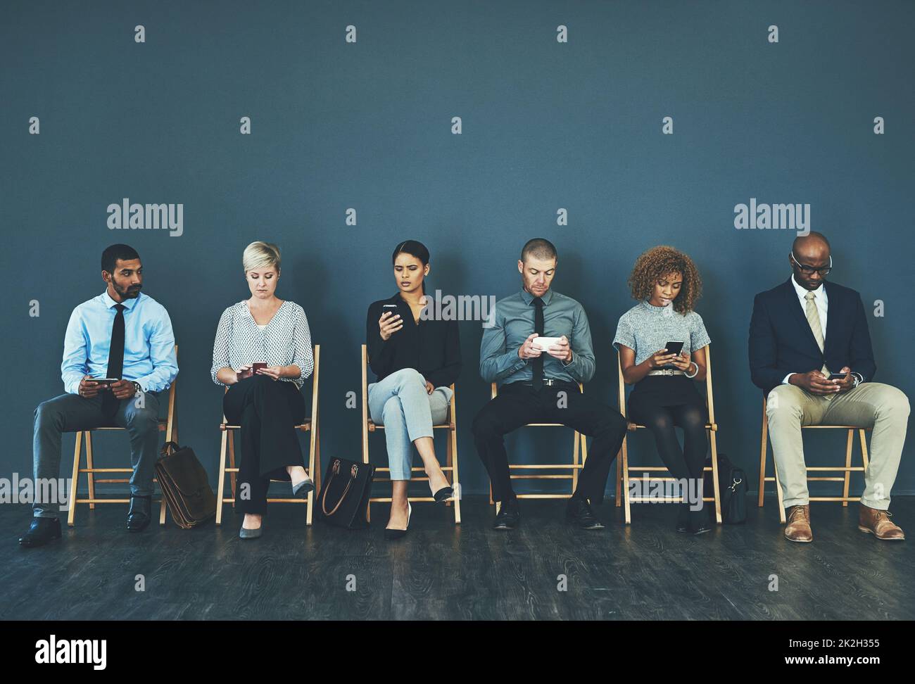 Il pourrait être n'importe qui de nous. Photo d'un groupe de gens d'affaires bien habillés assis dans la file en attendant d'être interviewés. Banque D'Images