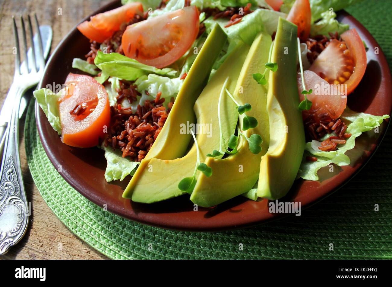 Délicieuse salade verte fraîche avec tomate, avocat et riz rouge Banque D'Images