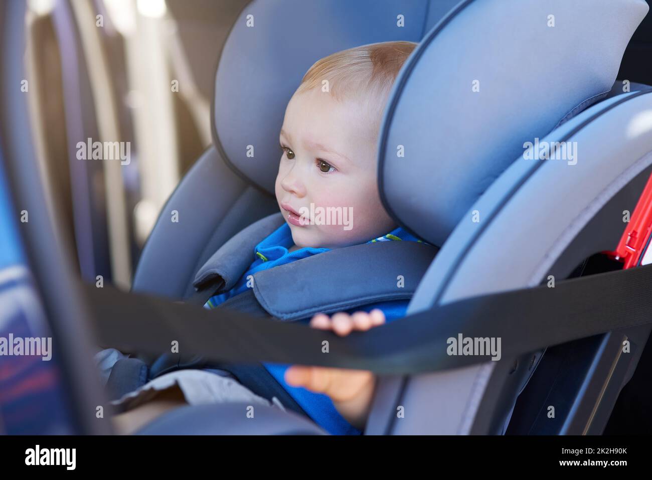 Assis en toute sécurité dans son siège. Photo courte d'un adorable bébé garçon assis dans un siège d'auto. Banque D'Images