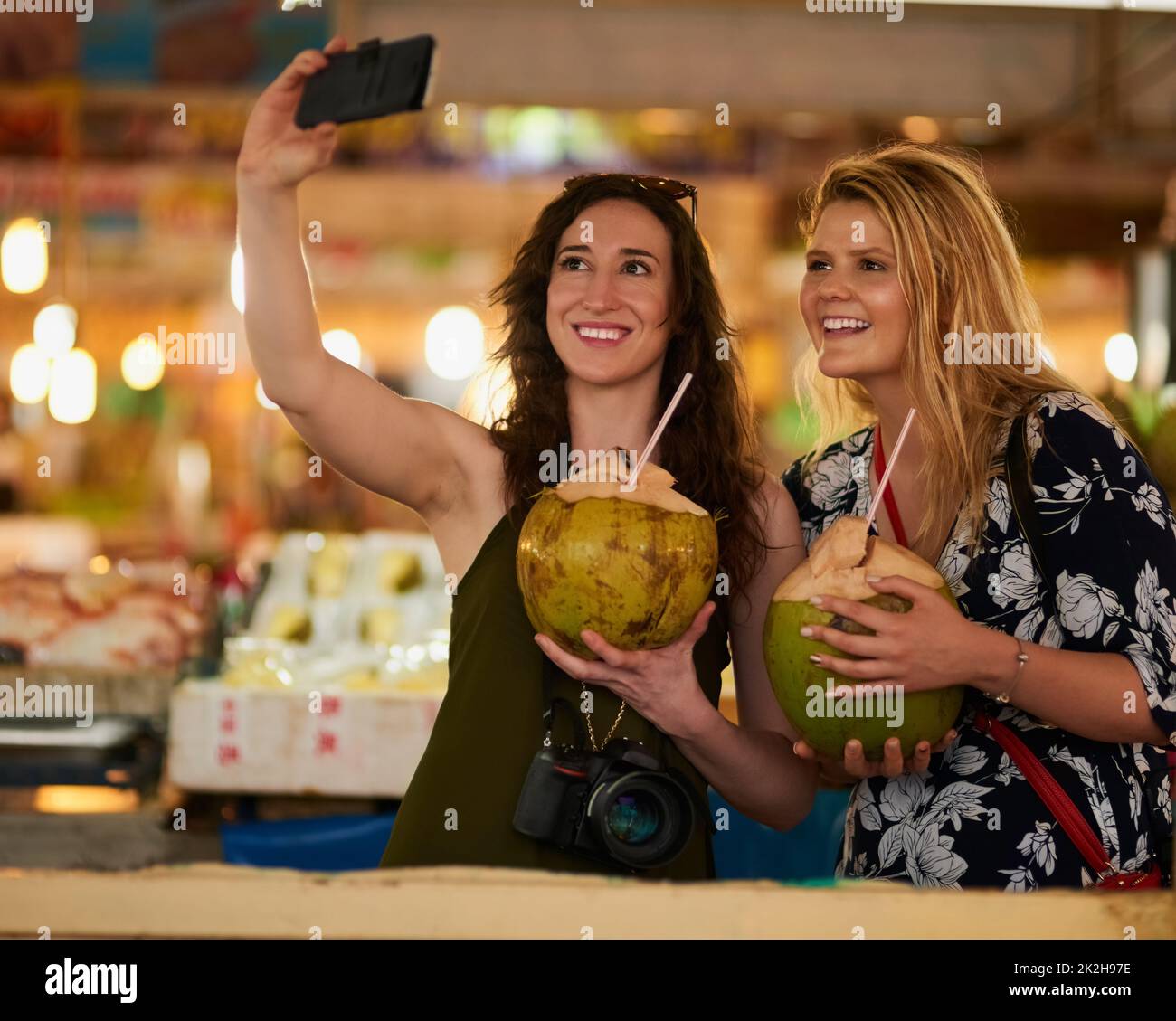 Je vous souhaite d'être ici. Photo de deux jeunes amis heureux prenant un selfie tout en dégustant des boissons exotiques en vacances. Banque D'Images