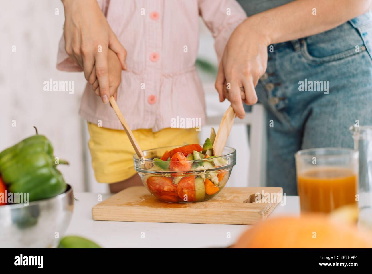 Maman et fille mélangent la salade avec des spatules en bois Banque D'Images