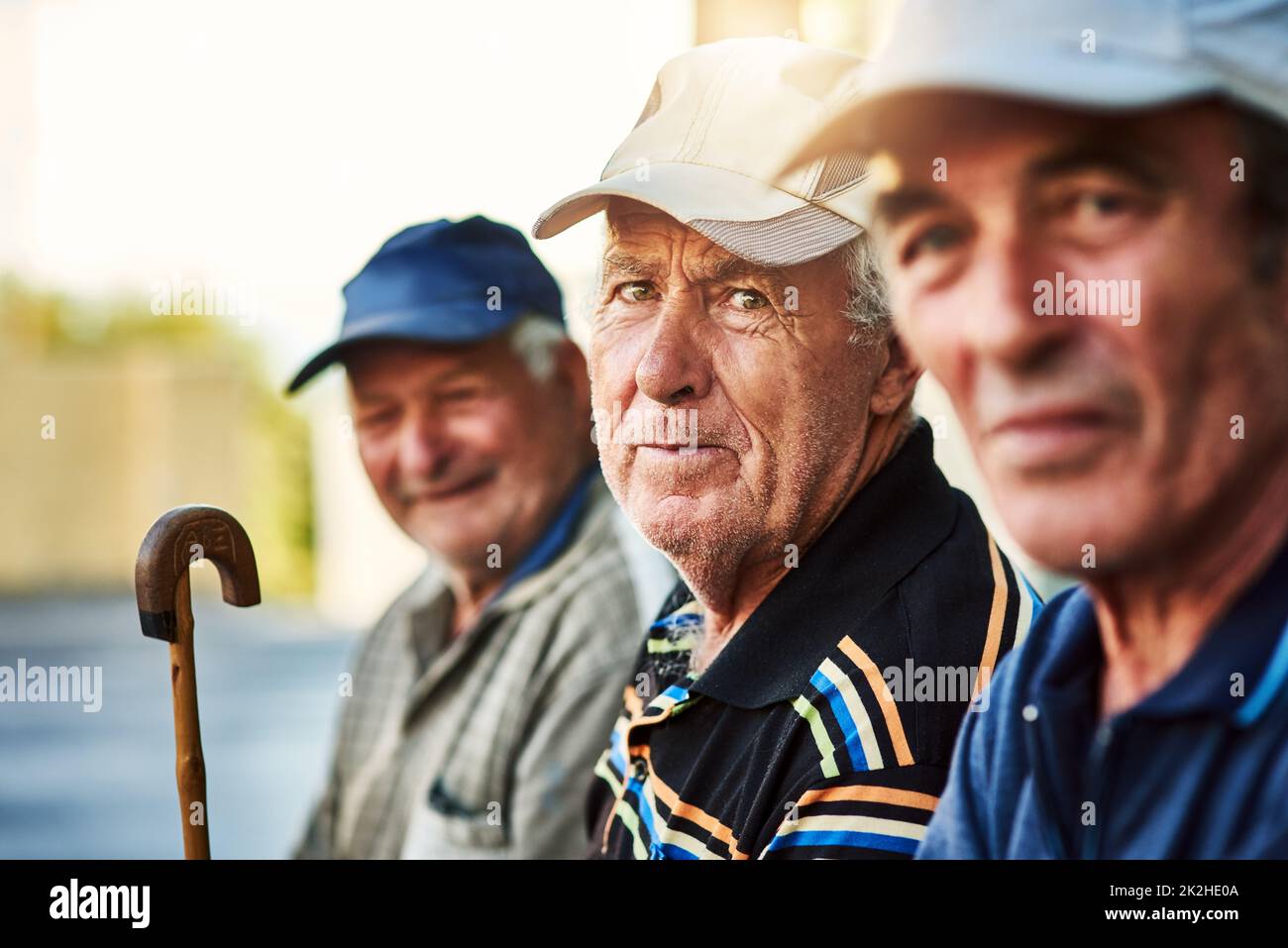 Les hommes de la ville. Portrait d'un groupe d'hommes âgés joyeux assis ensemble tout en regardant dans l'appareil photo à l'extérieur. Banque D'Images
