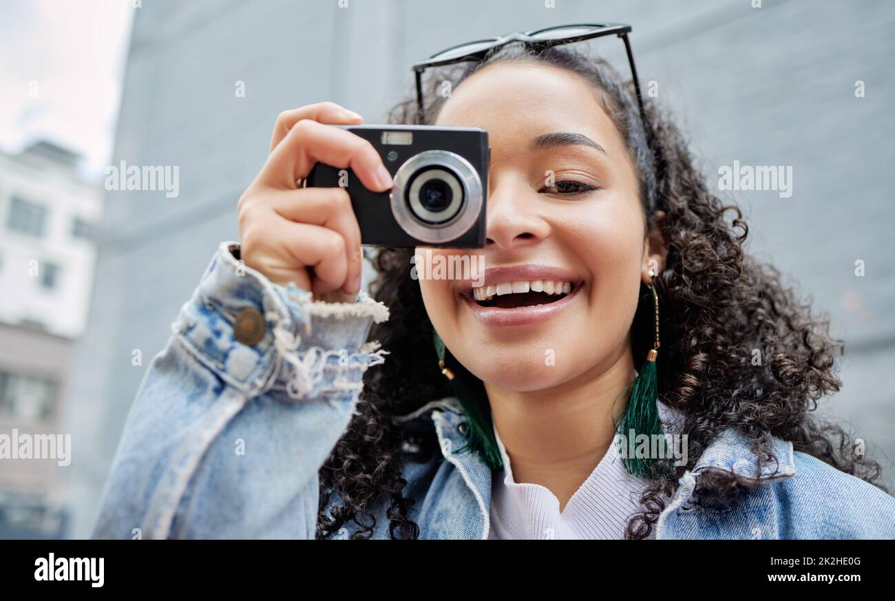 Souriez pour l'appareil photo Photo d'une jeune femme tenant son appareil photo tout en se tenant à l'extérieur. Banque D'Images