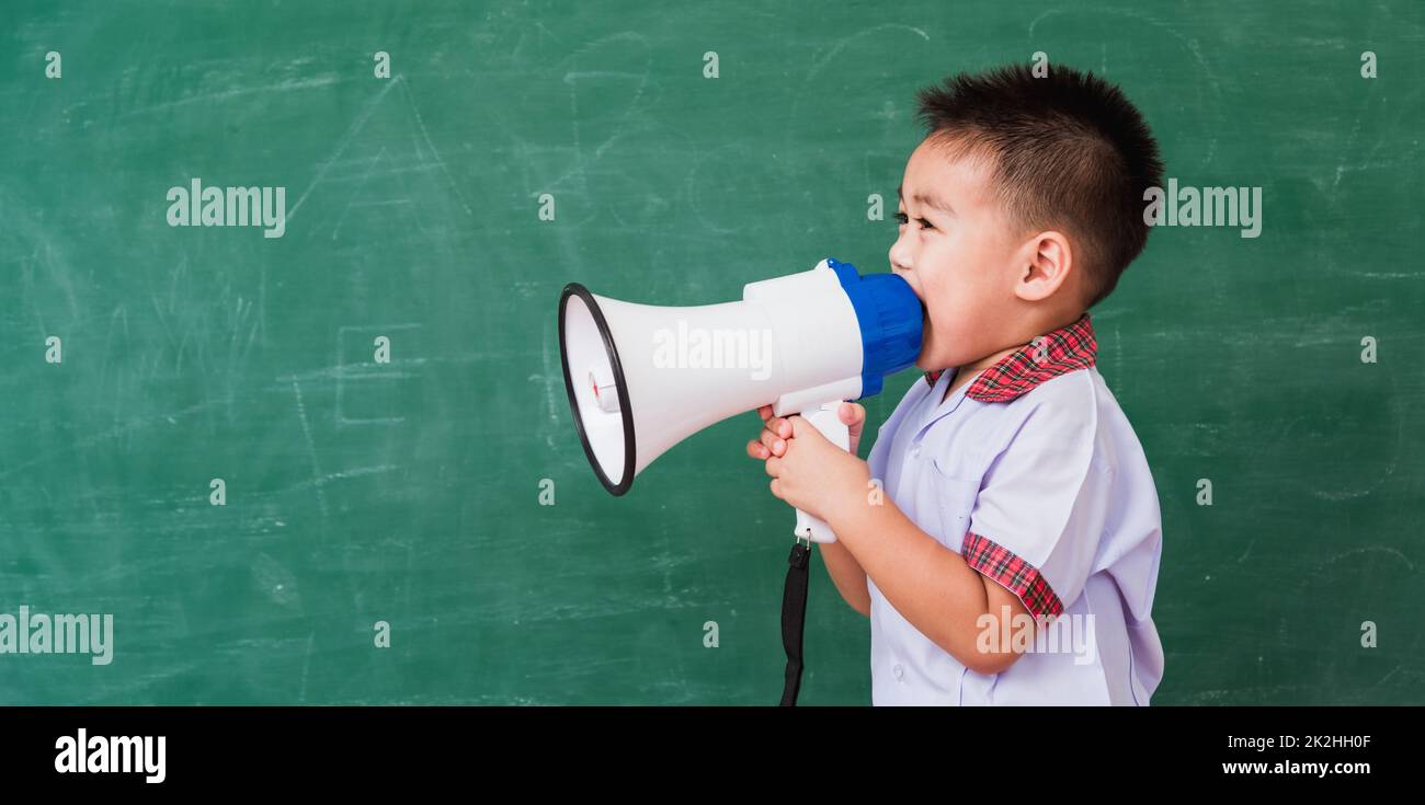 enfant garçon maternelle dans l'uniforme d'étudiant parlant par le mégaphone contre Banque D'Images
