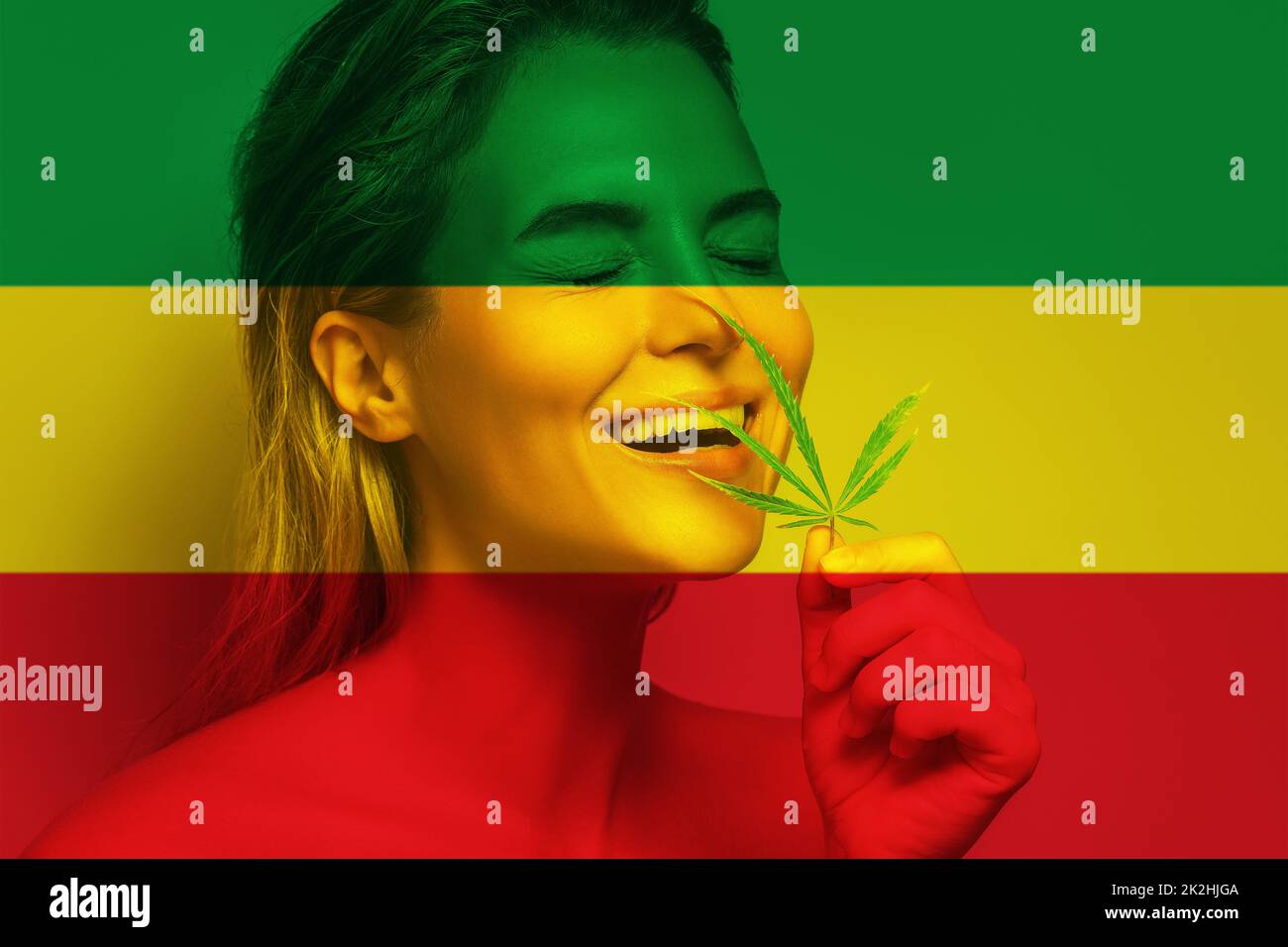 Belle femme avec une feuille de cannabis aux couleurs du drapeau Rastafarien Banque D'Images