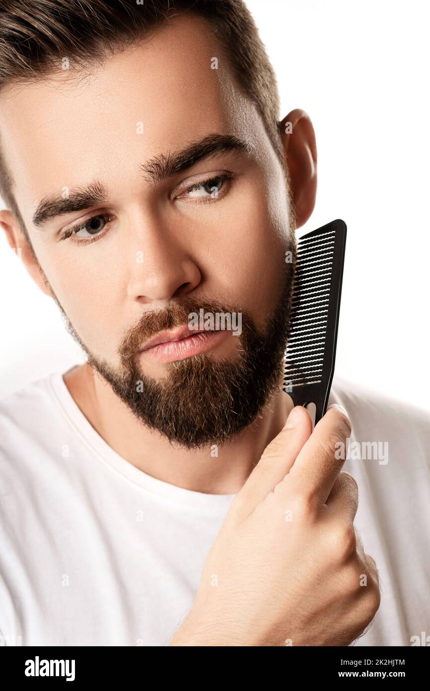 Beau homme bien entretenu peignant sa barbe Banque D'Images