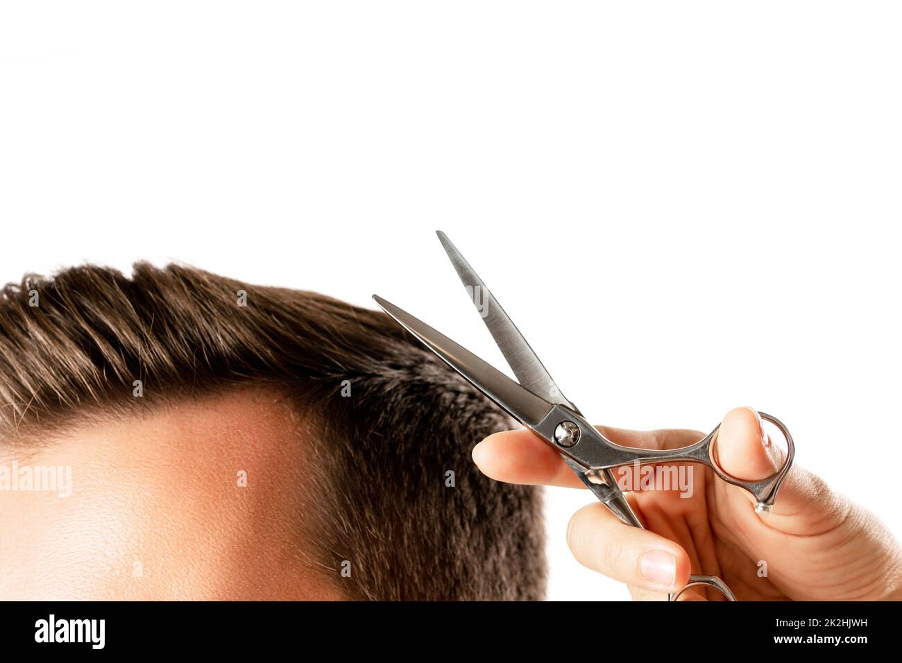 Main de coiffeur avec ciseaux et cheveux d'homme Banque D'Images
