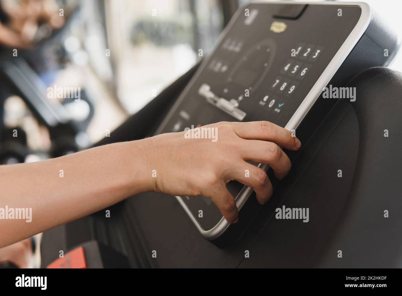 Femme changeant de réglages sur un tapis roulant dans une salle de gym Banque D'Images