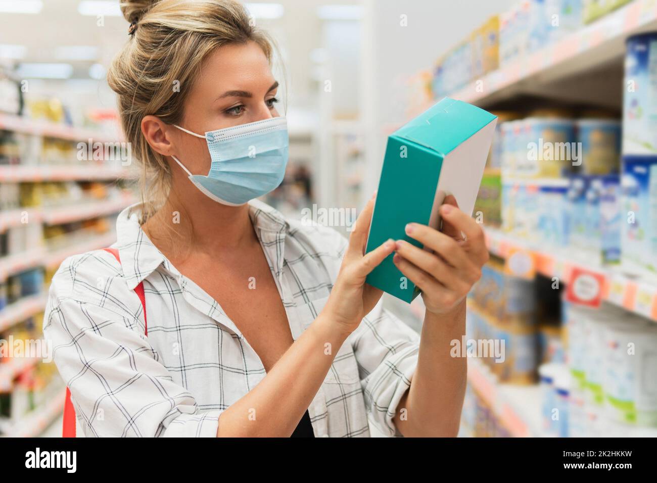 Une jeune femme portant un masque de prévention dans un supermarché pendant une pandémie de virus Banque D'Images