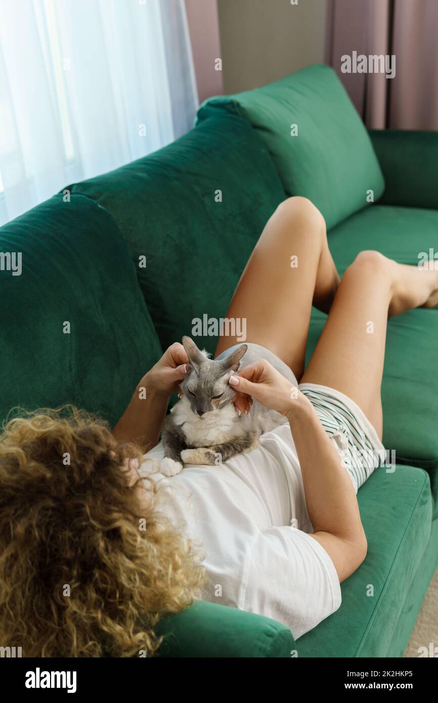 Jeune femme et son chat mignon allongé sur le canapé Banque D'Images