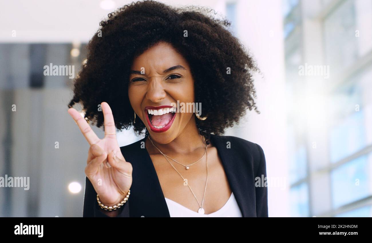 Portrait d'une jeune femme d'affaires confiante montrant un geste de paix dans un bureau moderne Banque D'Images