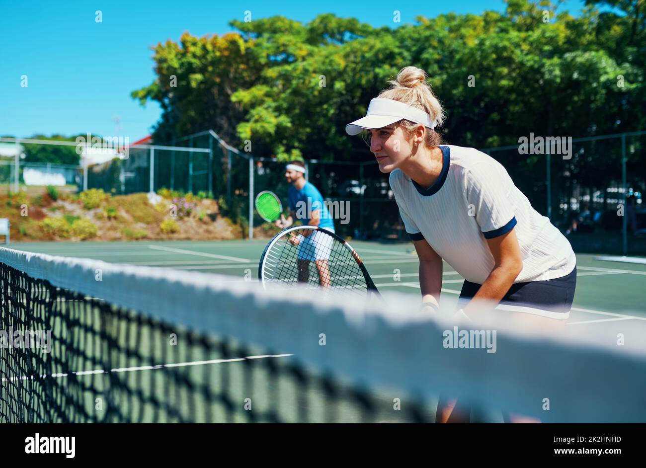 Laissez tout sur le terrain.Photo courte d'une équipe de tennis mixte jouant ensemble sur un court de tennis en plein air. Banque D'Images