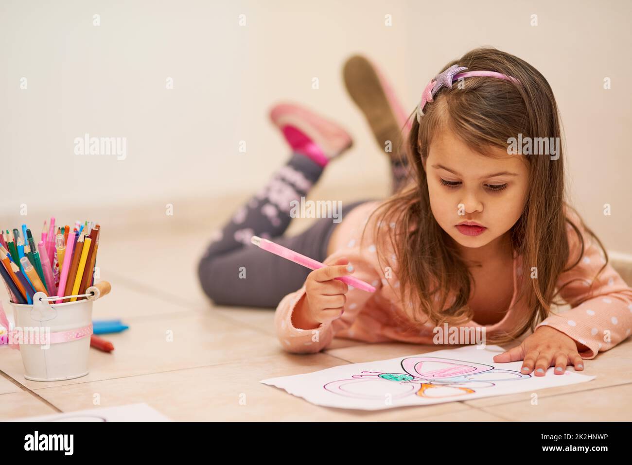 Se sentir à l'aise pour faire preuve de créativité. Photo d'une petite fille colorant dans une photo à la maison. Banque D'Images