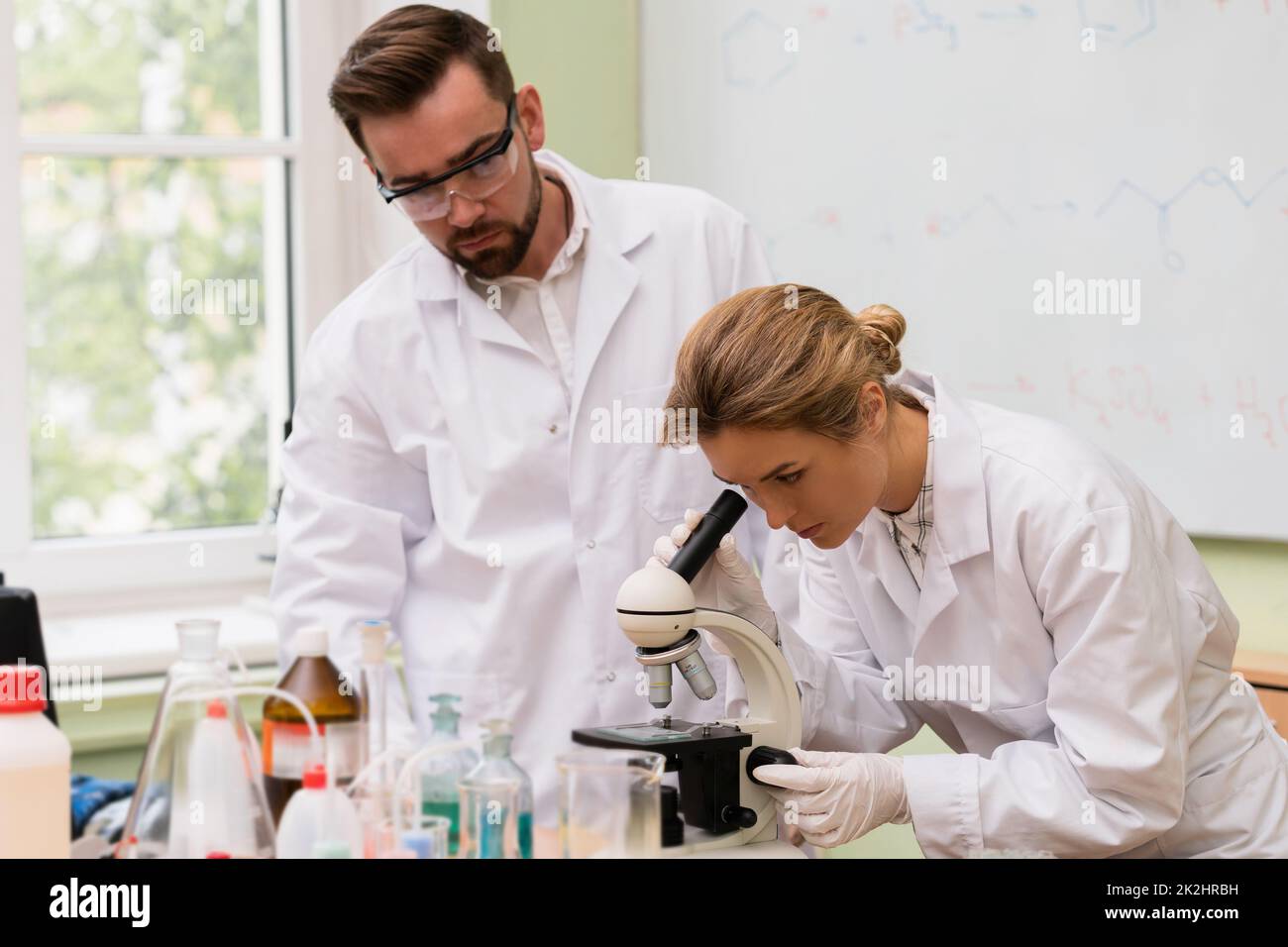 Deux collègues scientifiques utilisent le microscope pendant la recherche dans un laboratoire Banque D'Images