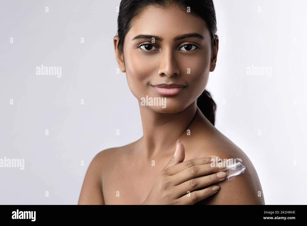 Belle femme indienne appliquant de la crème hydratante ou crème solaire sur son corps Banque D'Images
